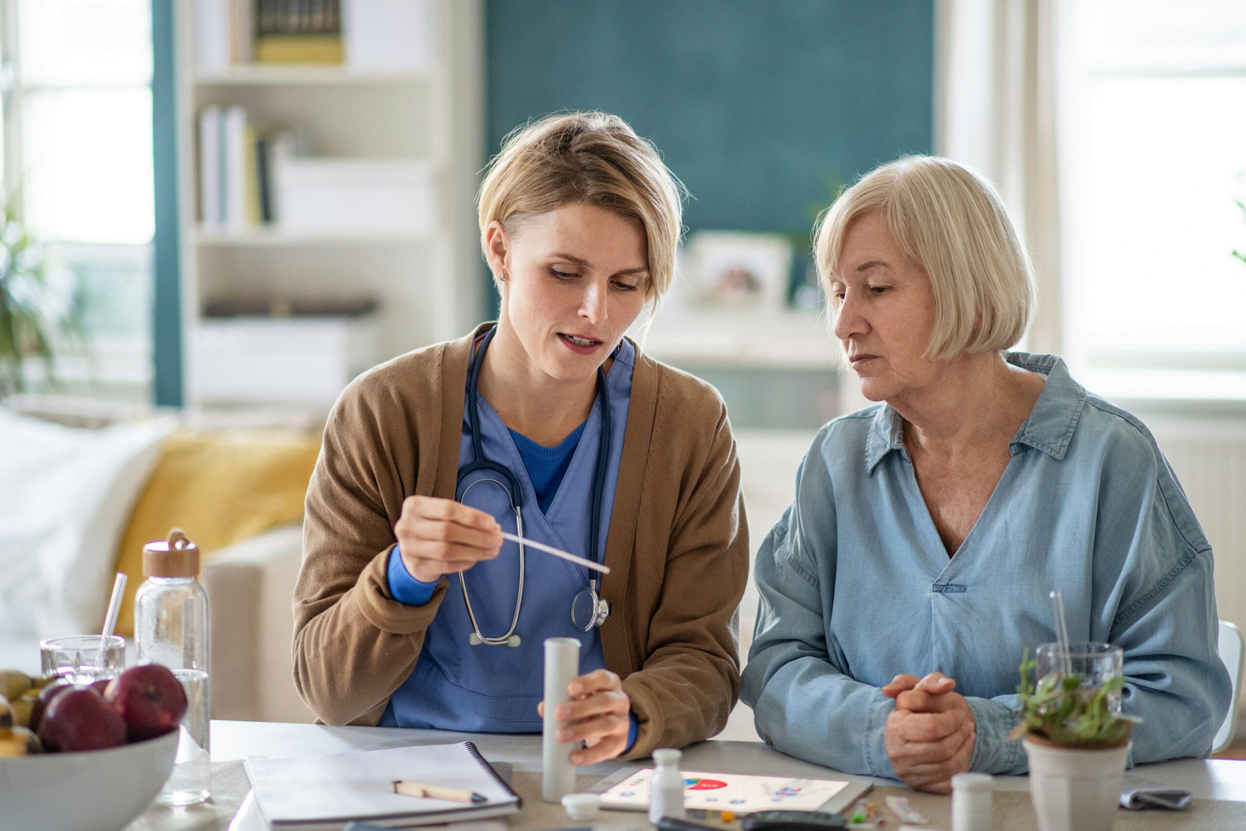 Nurse demonstrating a medical test to an older woman at a table