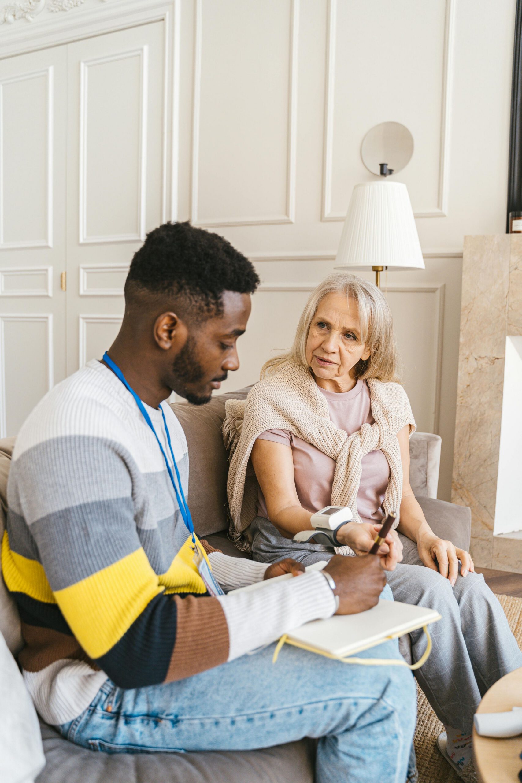 Caregiver reviewing notes with an elderly woman during a home visit