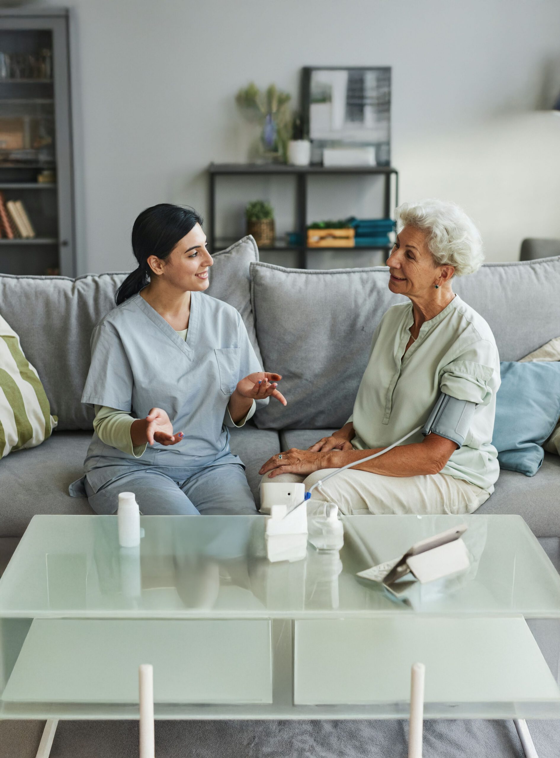 Caregiver sitting and speaking with an older woman, offering attentive support