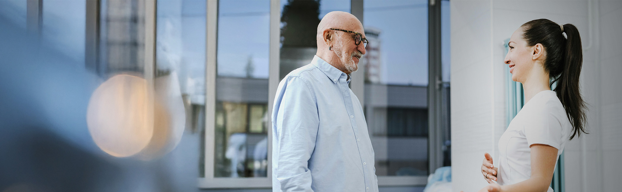 Caregiver and older man standing together and talking outside, sharing a calm and respectful conversation