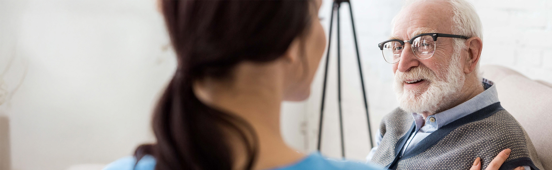 Caregiver speaking face-to-face with an older man, listening closely and offering attentive, personal support