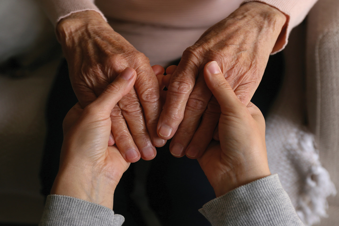 Caregiver gently holding a patient’s hands, offering steady comfort and reassurance during a moment of care