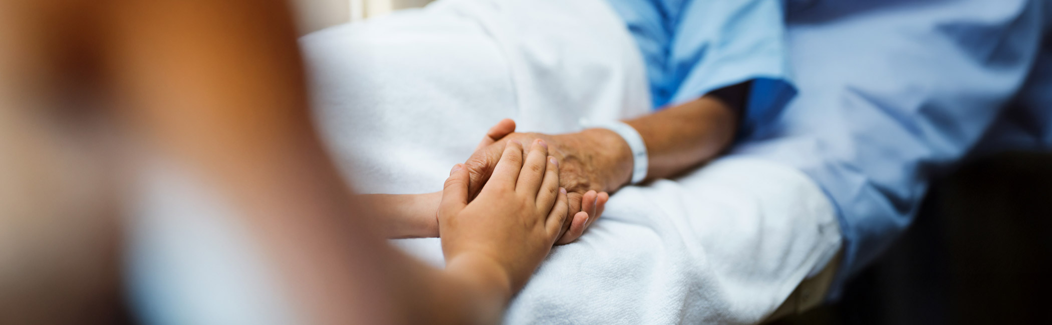 Healthcare provider gently holding a patient’s hand, offering reassurance and personal support during care