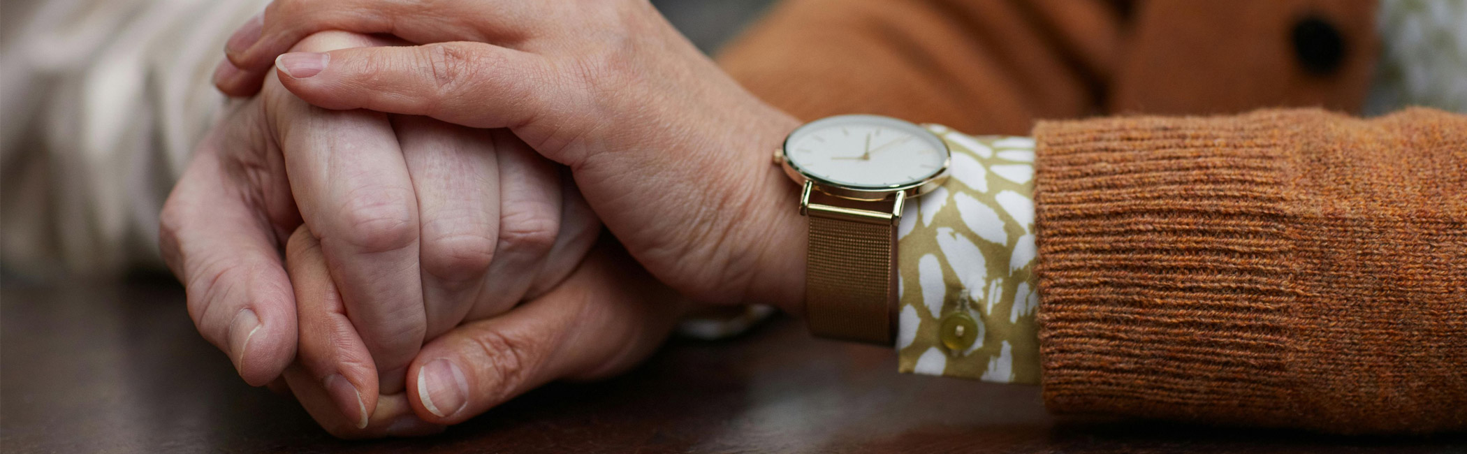 Caregiver resting a reassuring hand over another’s, offering calm support and presence during a personal moment