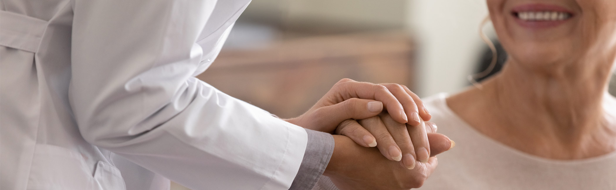 Healthcare provider gently holding a patient’s hand, offering reassurance and personal support during care