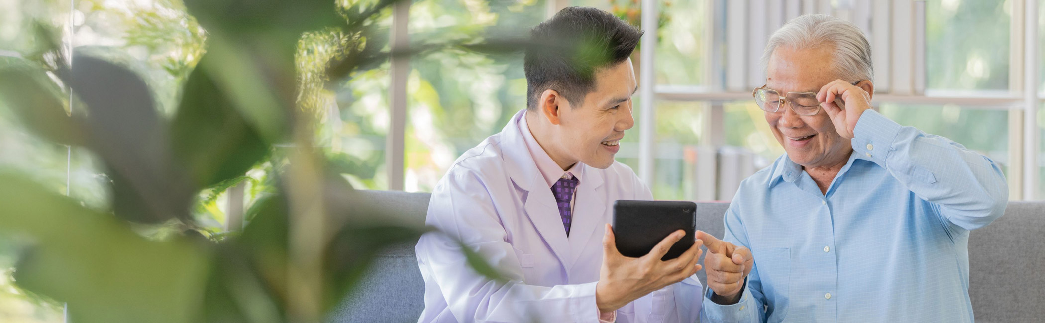 Care provider sharing a tablet with an older man, creating a moment of engagement and connection
