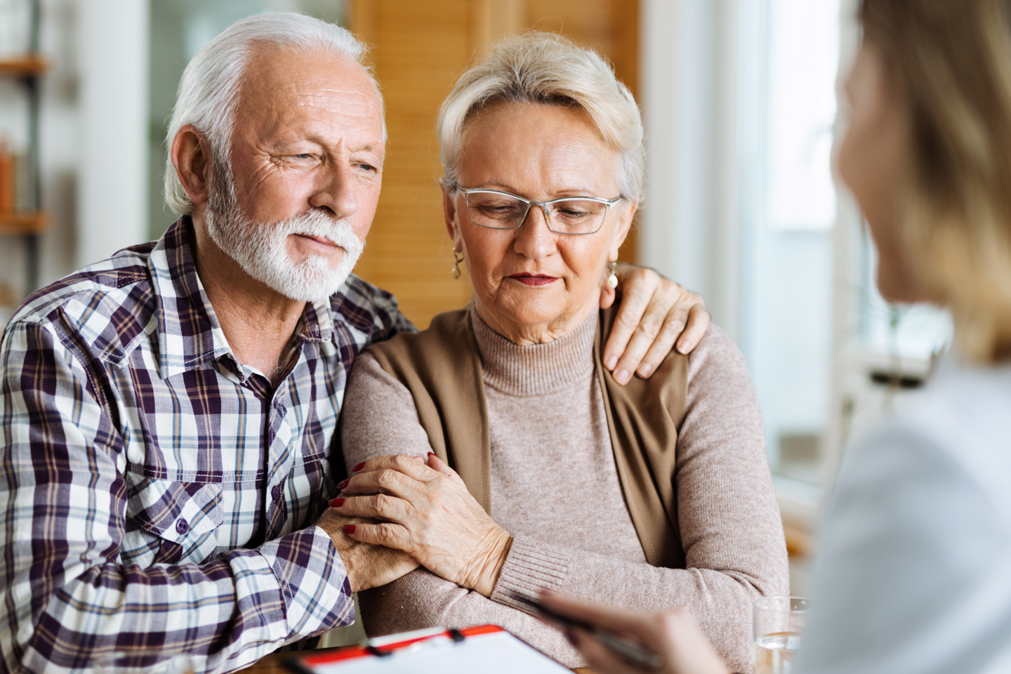 Older couple sitting closely together during a conversation with a care provider, seeking guidance and support in a shared moment