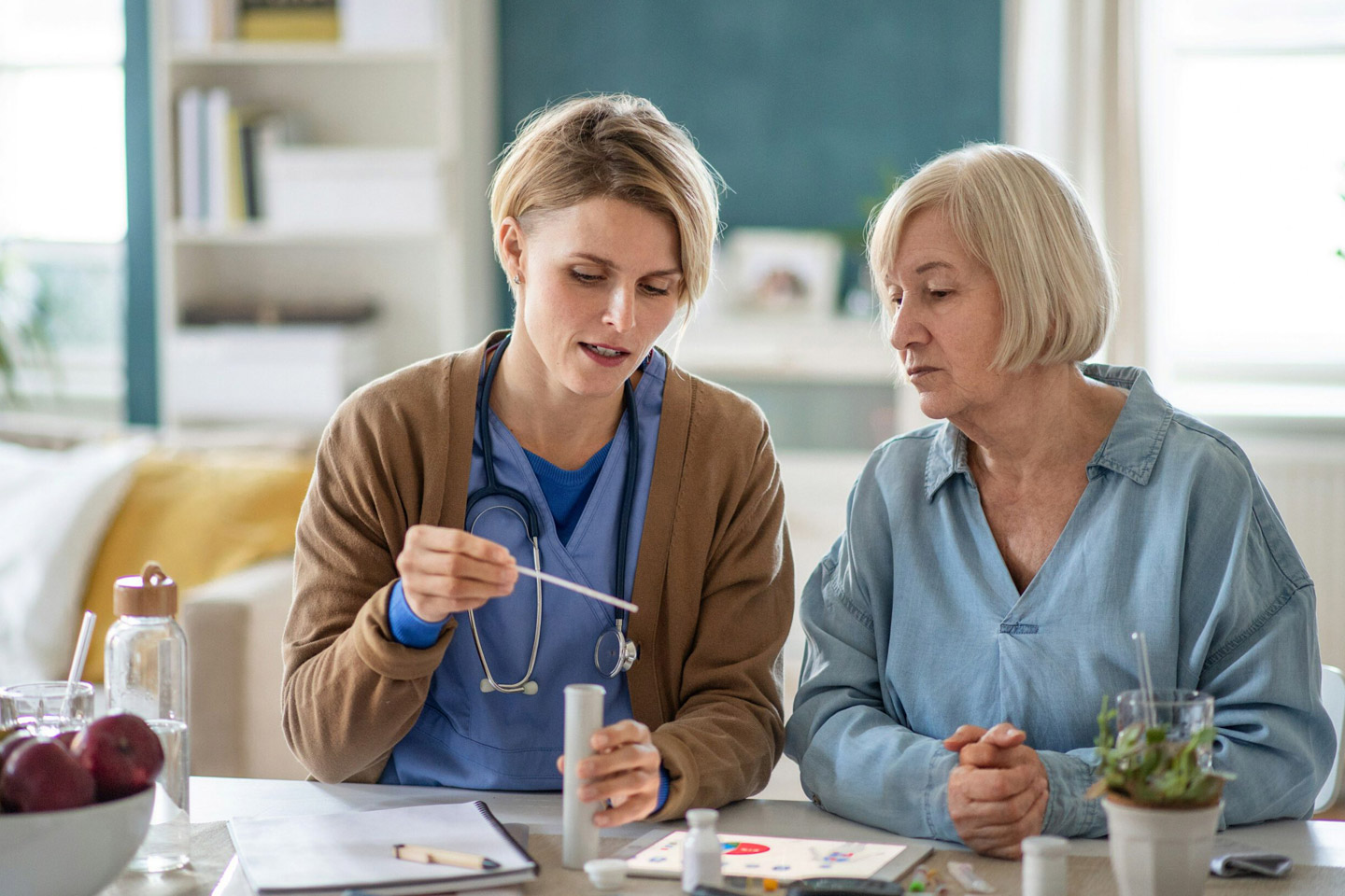 Care provider demonstrating a simple at-home test for an older woman, offering clear instruction and guidance