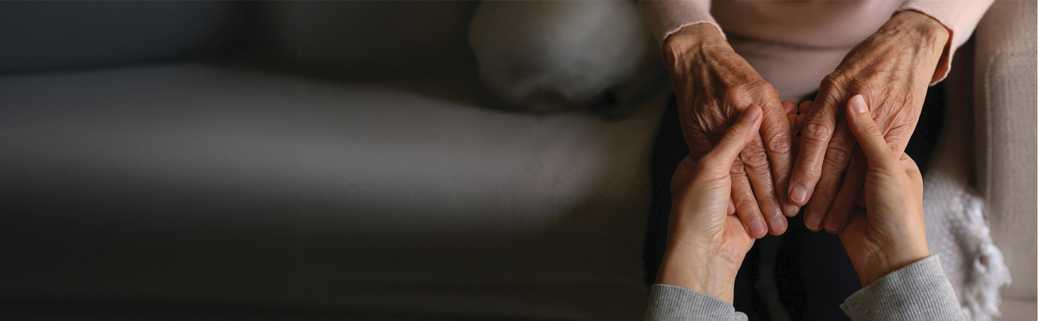 Caregiver holding an older woman’s hands, providing calm, one-on-one reassurance and presence