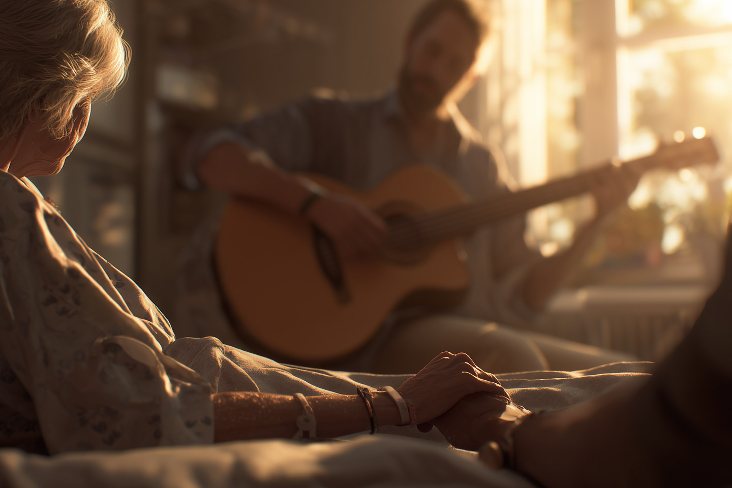 Patient resting in bed holding a loved one’s hand while music is played nearby, creating a peaceful and comforting environment