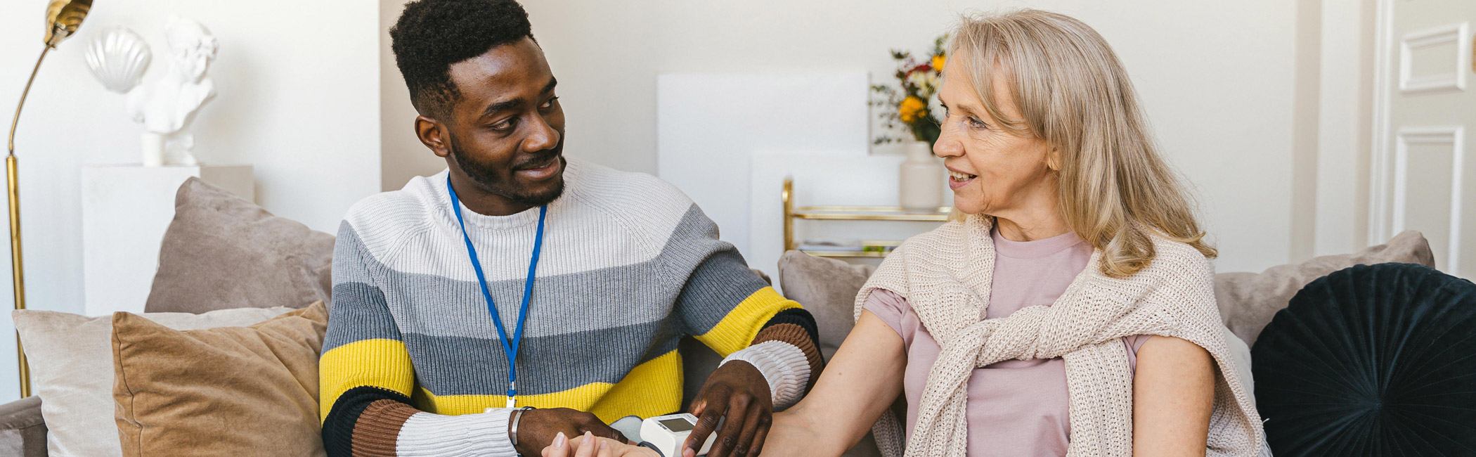 Caregiver assisting an older woman with a medical device at home, providing attentive and personalized care