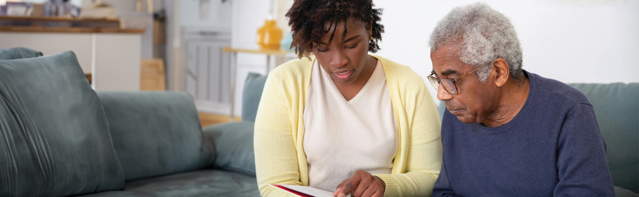 Caregiver sitting with an older man and reviewing information together, offering clear guidance and patient support