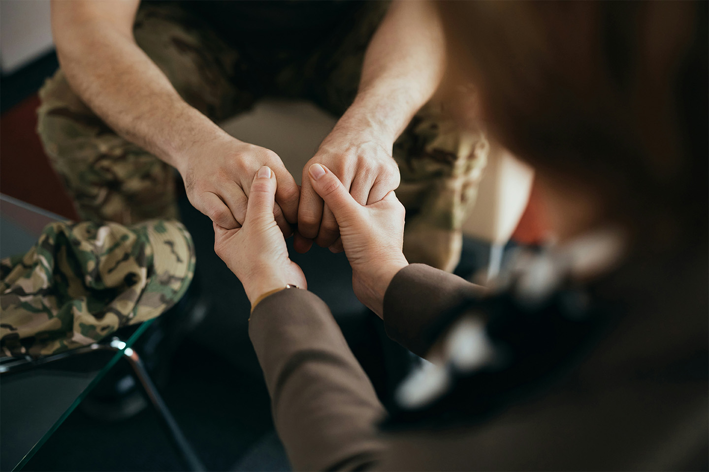 Caregiver holding a veteran’s hands during a supportive conversation, offering reassurance and steady presence