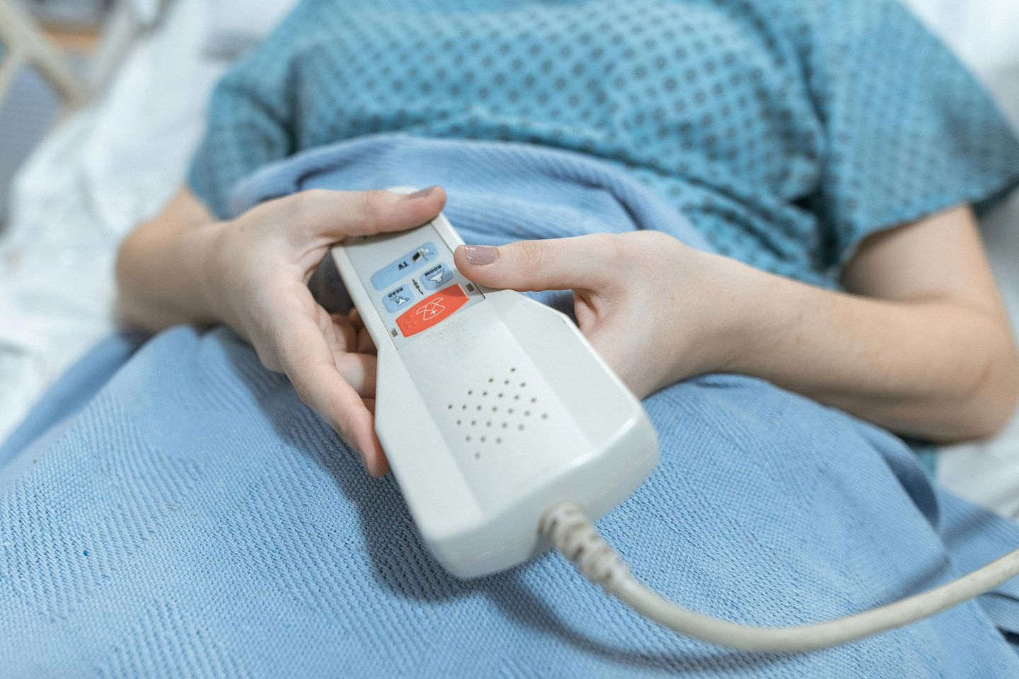 Patient holding a call button in bed, highlighting access to immediate support and responsive care