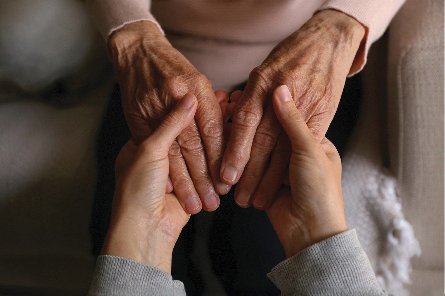 Caregiver gently holding an older woman’s hands, offering comfort and steady, personal reassurance