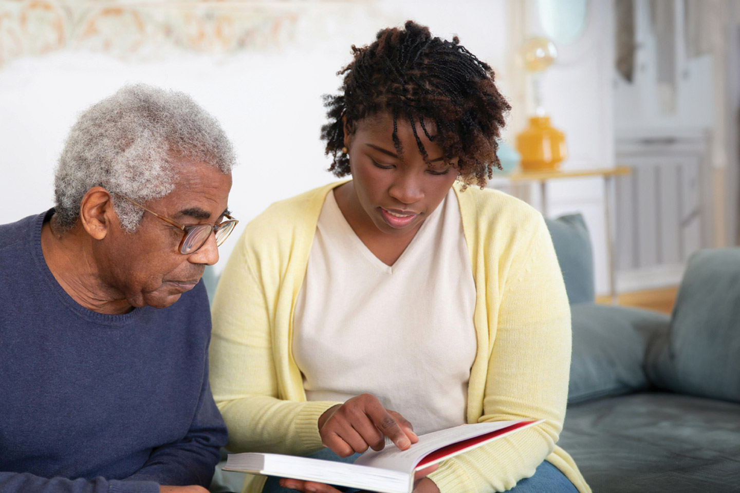 Caregiver sitting with an older man and reviewing information together, offering clear guidance and supportive conversation